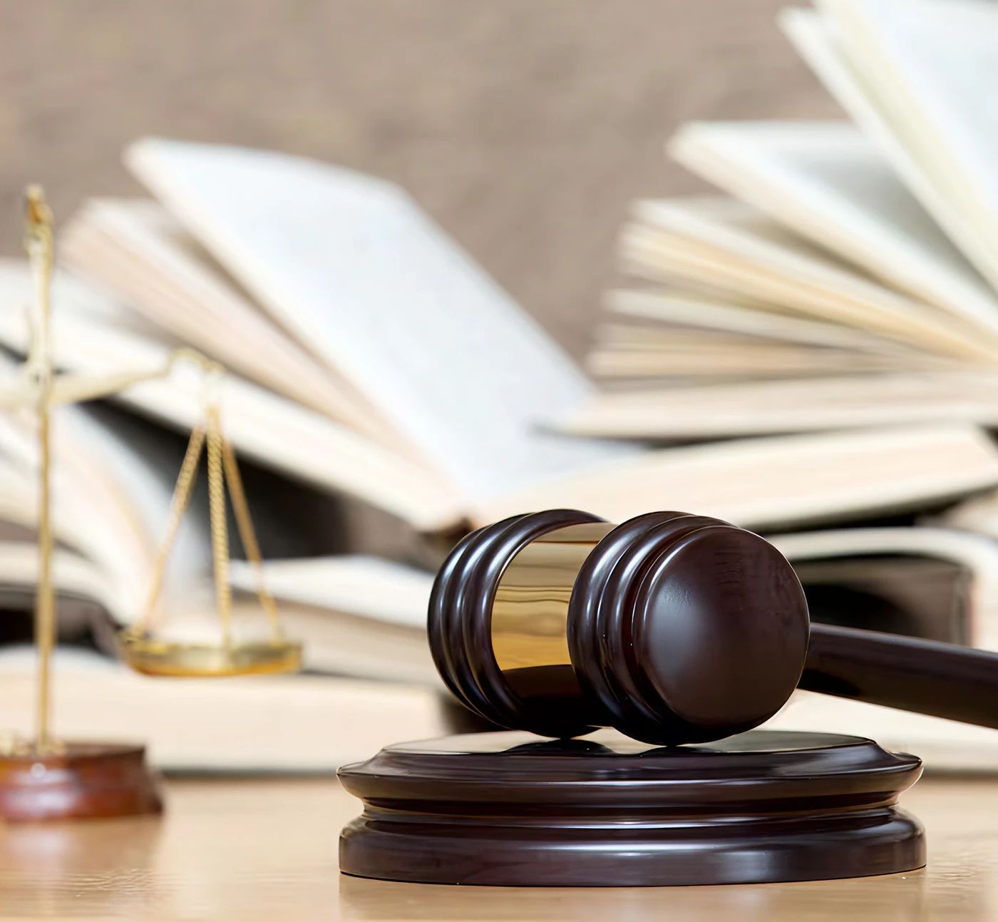 A judge's gavel and scales of justice on a desk of open law books